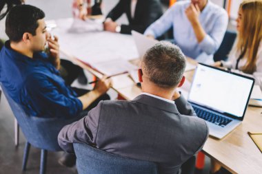 Bir grup profesyonel ortak, ofis şirketinde iş günlerinde iş çözümleri aramak için verimli bir brifing veriyor, erkek ve kadın meslektaşlar dizüstü bilgisayarın kullanım teknolojisi hakkında konuşuyorlar.