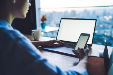 Resmi olarak tanınmayan kadın işçiler dizüstü bilgisayarda yazarken ve akıllı telefonlara bakarken modern ofiste bir bardak sıcak içecekle proje üzerinde çalışırken