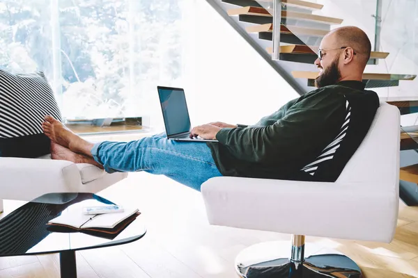 Zijaanzicht Van Vrolijke Man Zittend Fauteuil Met Gekruiste Benen Laptop — Stockfoto