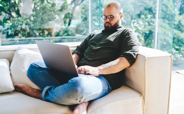 Grijulos Barbă Sex Masculin Stând Canapea Picioare Încrucișate Folosind Laptop — Fotografie, imagine de stoc