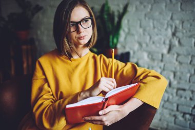 Görme koruması için optik gözlüklü düşünceli zeki bir öğrenci. Çok satan ilginç senaryolar üzerinde kafa yoruyor. Kısa saçlı, kısa saçlı, eğitim kitabı ve öğrenimi olan genç bir kadın.