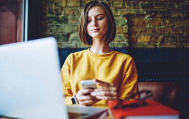 Milenyum bilişim uzmanı, modern cep telefonu teknolojisini kontrol ediyor. Kafe içinde uzaktan çalışıyor. 20 'li yaşlarda yetenekli bir kadın internet sitesinde internet üzerinden rezervasyon ve bankacılık yapmak için akıllı telefon cihazı kullanıyor.