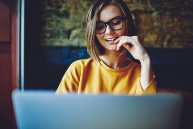 Optik gözlük takan yetenekli kadın blogcu laptopta sosyal ağların keyfini çıkarırken 4G internet kullanıyor, gözlüklü beyaz bir kadın web yayını arıyor.