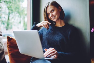 Modern dizüstü bilgisayarlı neşeli yeniyetme kız portresi kameraya gülümserken birlikte çalışma alanında internete bağlanan mutlu beyaz kadın blogcu netbook teknolojisini boş zamanlarında kullanıyor.