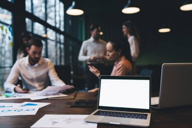 Yaratıcı çalışma alanındaki boş ekranlı bir ağ, birlikte çalışan ve akıllı telefonlar ve belgeler kullanan iş arkadaşlarıyla dolu.