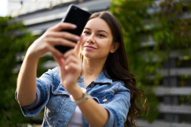 4 gramlık internet bağlantısı için ön cep telefonu kamerasını kullanan çekici bayan turist, Kafkasyalı gezgin kız video bloğunu sosyal medyaya aktarmak için etkiliyor