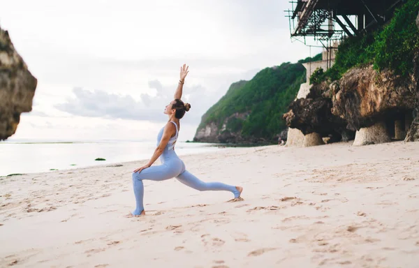 巴厘岛炎热多云的天气 在沙滩上练习瑜伽的苗条身材的年轻女运动员的侧视图 — 图库照片