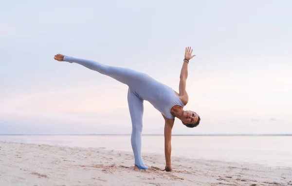 夏季穿着运动服 光着脚的柔韧女子在沙滩上做瑜伽的侧视图 — 图库照片