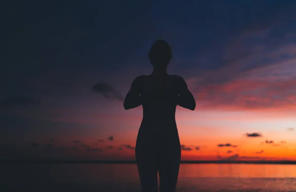 安贾利 穆德拉站在巴厘岛海滩上练习瑜伽的女性形象轮廓 粉色和橙色日落的天空在后面 — 图库照片