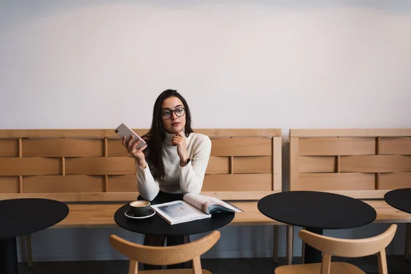 Mulher Cuidadosa Suéter Branco Óculos Usando Celular Enquanto Descansa Mesa — Fotografia de Stock