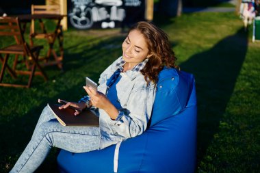 Çizim defteri çizen mutlu Kafkasyalı öğrenci modern cep telefonu cihazında SMS mesajları aldı, neşeli hipster kız web sitesinde ağ kurarken medya uygulaması yüklüyor