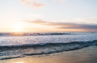Köpüklü büyük dalgalar okyanusun ıslak kumlu sahillerinde güneşli bulutlu gökyüzüne karşı egzotik Bali 'de