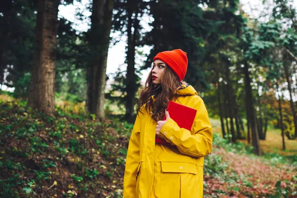 黄色のレインコートと赤い帽子の若い貴族の女性の低角度と秋に絵の森を楽しむ本と — ストック写真