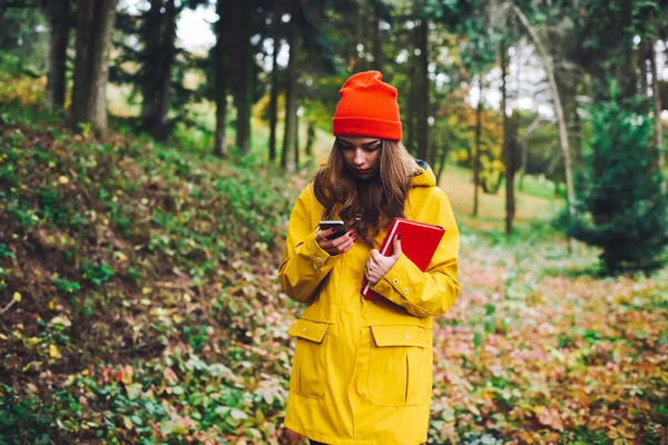 Young Concentrated Female Yellow Raincoat Red Hat Book Reading Message — Stock Photo, Image