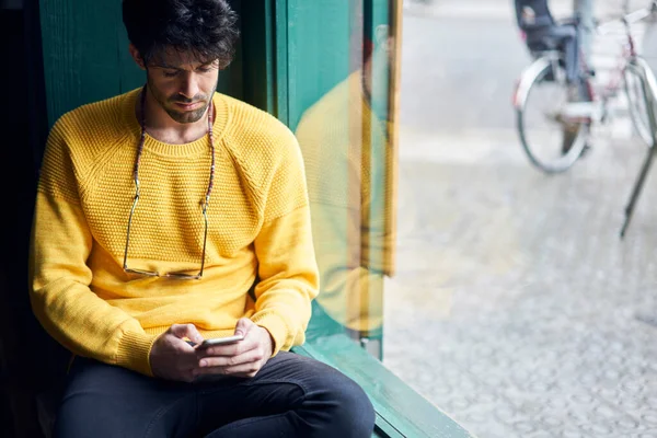 Crop Young Bearded Man Yellow Sweater Eyeglasses Using Smartphone While — Stock Photo, Image
