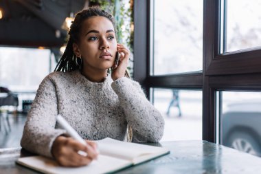 Afro örgülü zeki bir kız gezici danışmanlık konuşmaları sırasında bilgilendirici notlar hakkında konuşuyor. Koyu tenli kız öğrenci, ders hakkında konuşmak için üniversite arkadaşını çağırıyor.