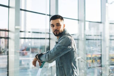 Ofisteki panoramik pencerenin önünde dikilirken omuzlarının üzerinden bakan bıyıklı ve kol saati olan odaklanmış girişimci