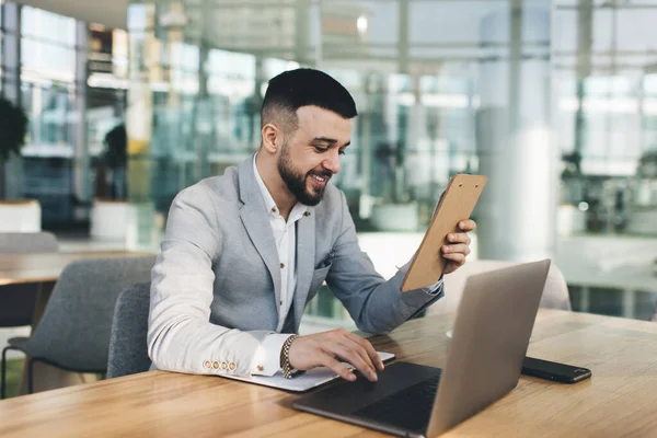 从事正规工作的年轻男性企业家在现代工作空间工作时 手拿笔记本坐在办公桌旁 上网浏览 — 图库照片