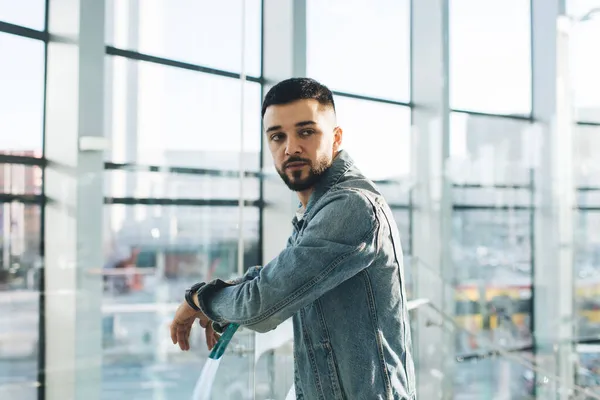 Ofisteki panoramik pencerenin önünde dikilirken omuzlarının üzerinden bakan bıyıklı ve kol saati olan odaklanmış girişimci