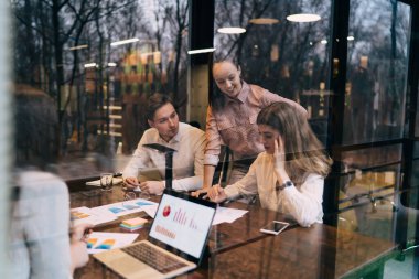 Çağdaş ofiste beyin fırtınası yaparken bir grup genç meslektaşın belgeler ve aletlerle masada toplanması sayesinde.