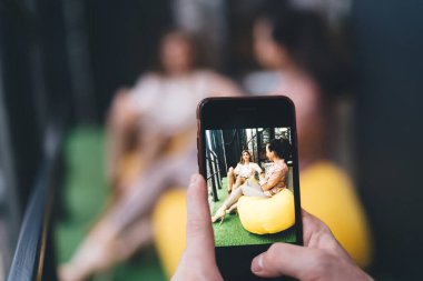 Tanımlanamayan bir adam resmi olarak bayan arkadaşlarının fotoğrafını çekiyor. Fasulye torbalarının üzerinde oturuyor ve akıllı telefonlarda balkonda gülümsüyor.