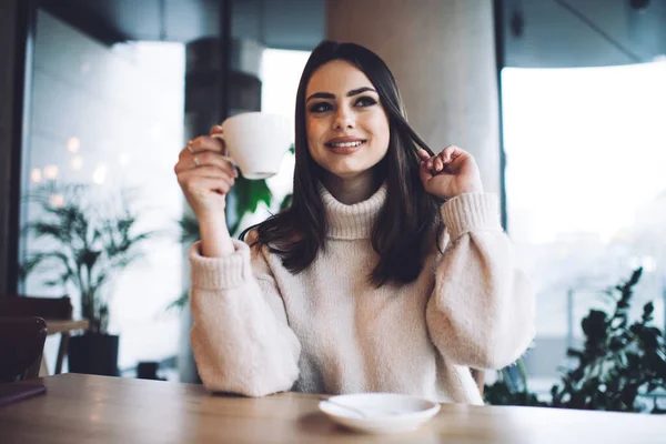 ホットコーヒーを飲みながら カフェで時間を過ごしている間に笑顔と離れて見てカジュアルな服装で幸せな女性 — ストック写真