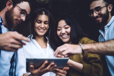 Modern ofis alanında çalışırken içerik çeşitliliğinin düşük açısı günlük giysiler içinde gülümseme ve tablet tarama