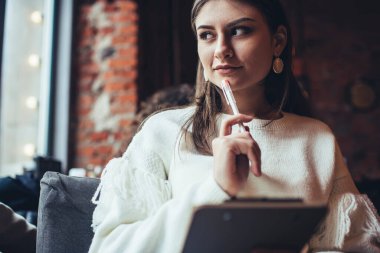 Kafede elinde not defteriyle oturmuş projeyi düşünürken beyaz günlük süveter giyen hasretli kız öğrenci gözlerini kaçırıyor.