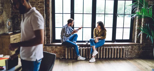 Jóvenes Colegas Enfocados Ropa Casual Sentados Alféizar Ventana Hablando Ideas — Foto de Stock