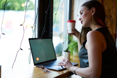 Milenyum kadın metin yazarı ve kahve modern dizüstü bilgisayarda web yayını okumak için, genç yetenekli bir kadın internet sayfası üzerinden video izlemek için kablosuz sayfaya göz atıyor.