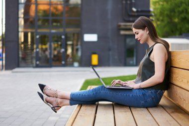 Bilgisayarlı yetenekli bir kadın internet sitesinde bilgi okuyor açık havada zaman geçiriyor, beyaz yeniyetme kız sosyal ağlardan video izliyor netbook teknolojisi kullanıyor.