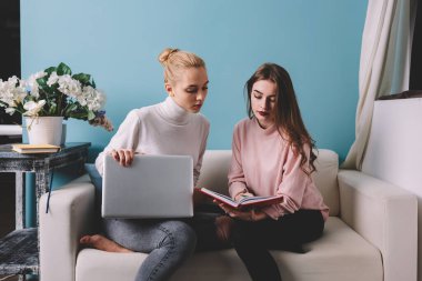 Düşünceli, uzaktan kumandalı işçiler kanepeye dizüstü bilgisayarlarıyla oturmuş yeni proje için fikir üretmeyi düşünüyorlar.