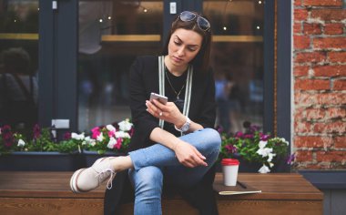 Genç seyahat blogcusu, modern cep telefonu aygıtında gezinen metinleri okuyor, günlük kıyafetleri giyen bin yıllık kız öğrenci dijital cep telefonu aygıtında çevrimiçi mesajlaşma sırasında e-posta aldı