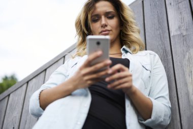 Çevrimiçi mesajlaşma için modern hücresel aygıt kullanan Kafkas blogger 20 'lerin altında, hipster kız mobil sosyal ağlarda medya içeriğini tararken metin yayınlarını okuyor