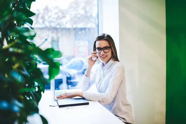 Mujer Alegre Freelancer Gafas Camisa Ligera Hablando Teléfono Móvil Mientras —  Fotos de Stock