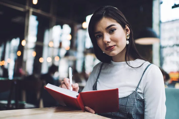 Busy Female Looking Camera Taking Notes Red Notepad While Sitting — Stock Photo, Image