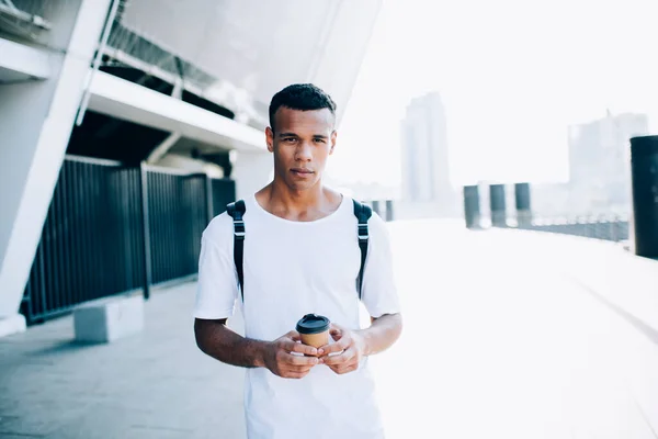 티셔츠를 아프리카 미국인 젊은이가 뜨거운 종이컵을 현대식 근처에서 가방을 거리에서 — 스톡 사진