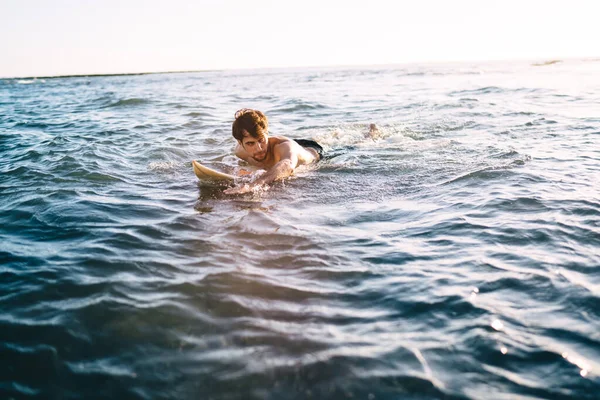 Ernstige Sportieve Jonge Shirtloze Man Drijvend Kabbelend Oceaanwater Liggend Surfplank — Stockfoto