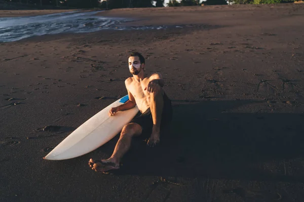 Poniżej Pełnej Długości Spokojnego Młodego Surfera Bez Koszuli Siedzi Piaszczystej — Zdjęcie stockowe