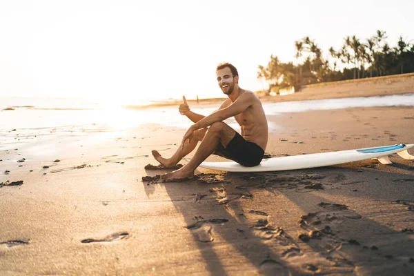 Widok Boku Bez Koszulki Wesoły Mężczyzna Surfer Patrząc Aparat Pokazując — Zdjęcie stockowe