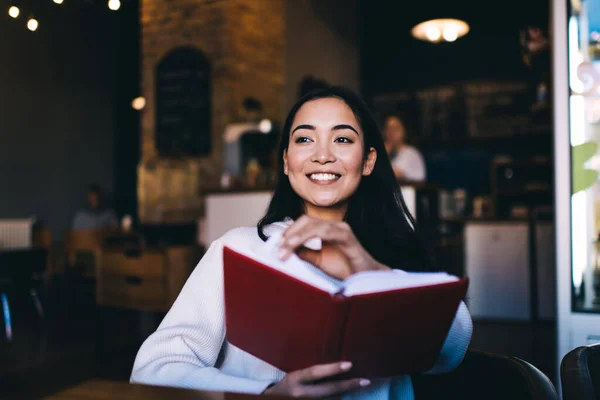 Gelukkig Jong Vrouwtje Met Lang Zwart Haar Lachend Leesboek Terwijl — Stockfoto