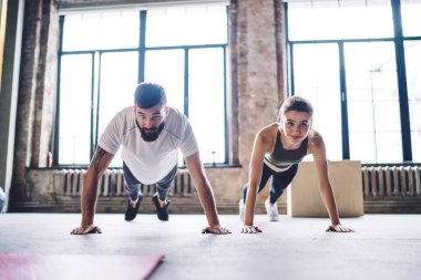 Kararlı erkek ve kadın çift modern spor salonunda birlikte antrenman yapıyorlar. Sağlıklı yaşam tarzlarını koruyorlar. Yakışıklı 20 'li yaşlarda erkek antrenör aktif giyimli bir kadınla antrenman yapıyor.