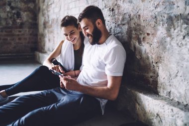 Gülümseyen güzel bayan ve yakışıklı erkek sporcu spor yaptıktan sonra bilgi edinmek için modern touchpad 'i kullanıyor. Birbirlerine aşık çiftler spor salonundaki tablet karşısında otururken aldıkları eğitimi paylaşıyorlar.