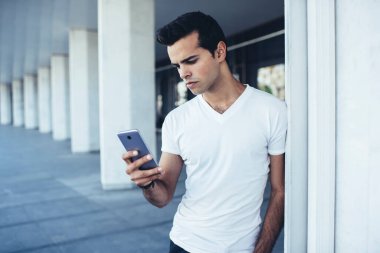 Sosyal medya ağlarında sohbet etmek ve mesajlaşmak için kablosuz bağlantı kuran genç hippi adam, akıllı telefon uygulaması üzerinden mesaj göndermek için cep telefonu mesajlarını kontrol eden bin yıllık adam.