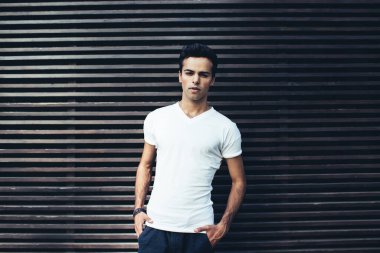 Beyaz tişörtlü beyaz adamın yarım boy portresi. Reklam alanında poz veren etiket alanı alanı olan beyaz tişörtlü. Açık havada kameraya bakan modacı.