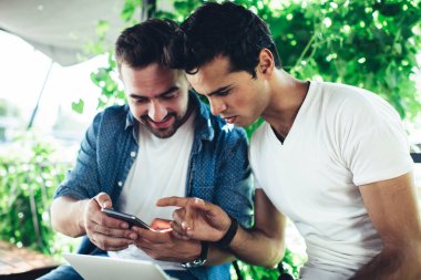 Genç hipsterlar modern cep telefonlarında internet üzerinden internet haberlerini kablosuz sayfada okumak için 4G 'ye bağlanıyorlar, beyaz erkek blogcular sosyal ağlarda cep telefonu kullanarak medya yayınlarını tarıyorlar.