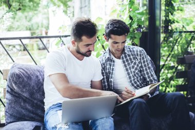 Kafe 'de bilgisayar ve ders kitabı analizi yapan beyaz öğrenciler organizasyon planını tartışıyorlar. Akıllı bilişim uzmanları birlikte uzaktan çalışırken yayın metnini tartışıyorlar.