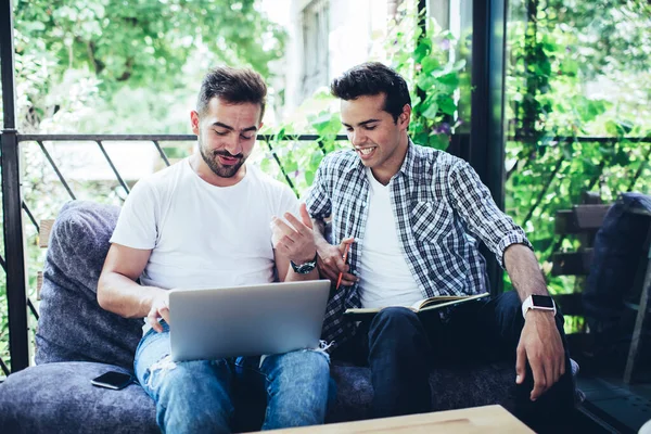 在互联网连接良好的街头咖啡馆里 白种人男性同事在讨论网络编程时 千禧年男性使用笔记本电脑观看视频 — 图库照片