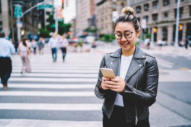 Gezici teknolojisi olan neşeli bir binyıl blogcusu solo tatiller sırasında kameraya gülümsüyor, elinde akıllı telefon cihazı olan mutlu Asyalı kız şehir seyahatinin tadını çıkarıyor.