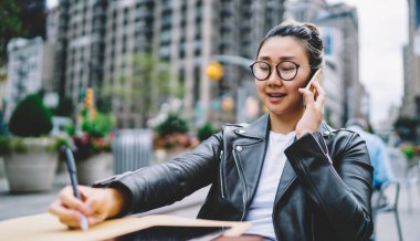 Çinli bir kadın uluslararası gezici sohbetler sırasında ders kitabına not alıyor. Milenyum modası geçmiş gözlüklü hippi kız kaldırımdaki kafede oturup telsiz konuşması istiyor.